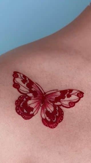 red ink butterfly tattoo on shoulder