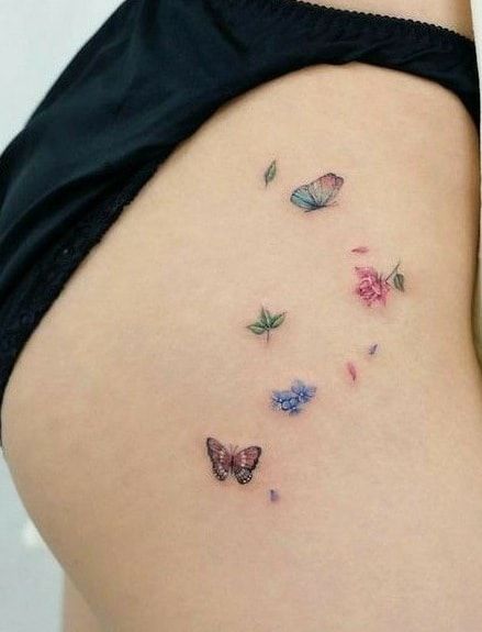 small delicate butterfly tattoo with flowers on thigh