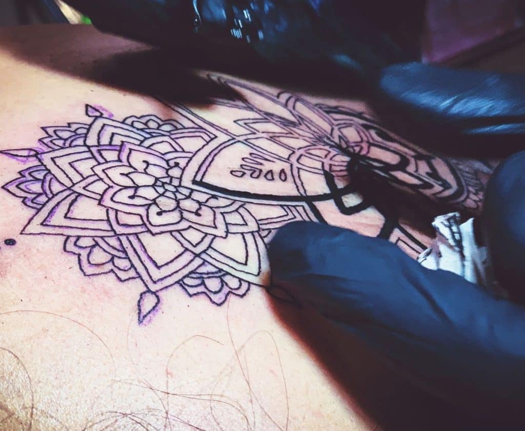 tattoo artist doing a mandala tattoo 