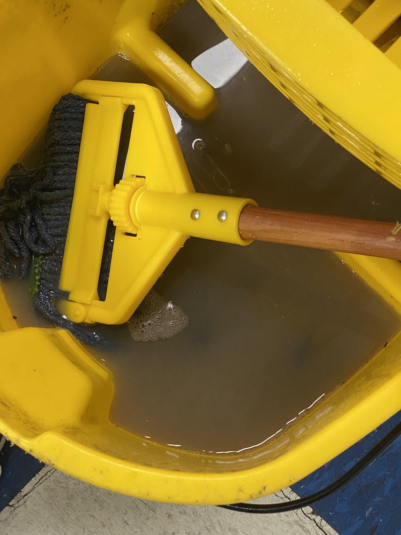 Mops Sitting in Buckets of Dirty Water on the Floor