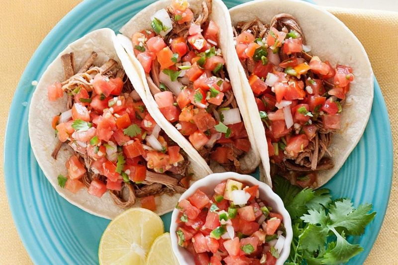 Topping Tacos with Shredded Lettuce and Diced Tomatoes