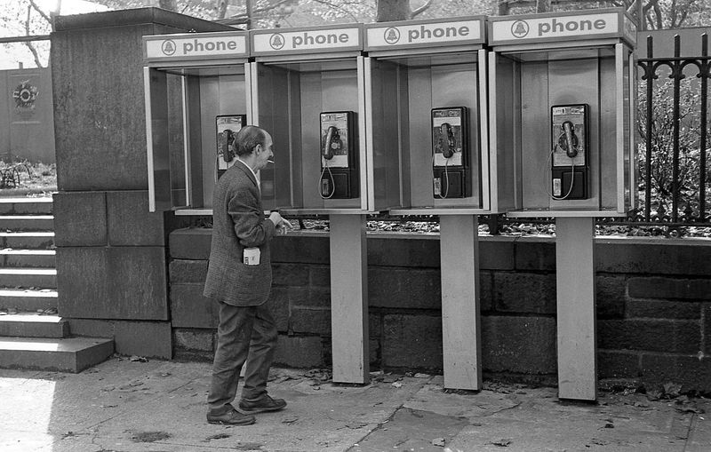 Standing in Line at a Pay Phone to Make a Call